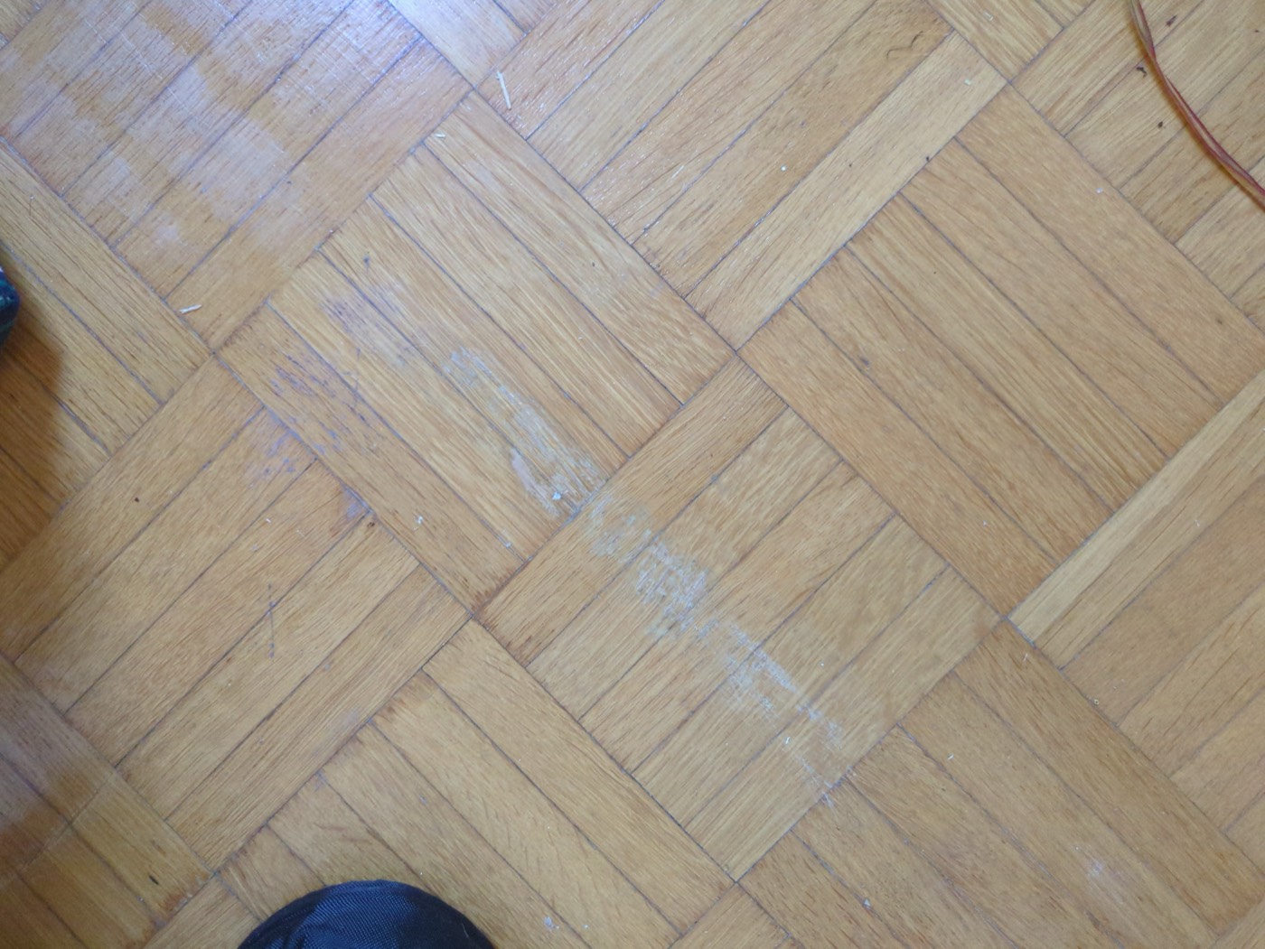 A pale streak in the parquet where the bed frame abraded the finish